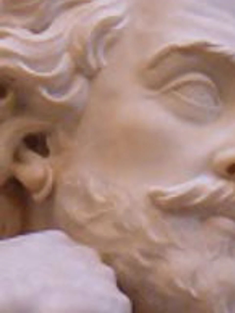 A marble statue of a man with a beard and curly hair, leaning on books with a thoughtful expression. Latin text is etched above.