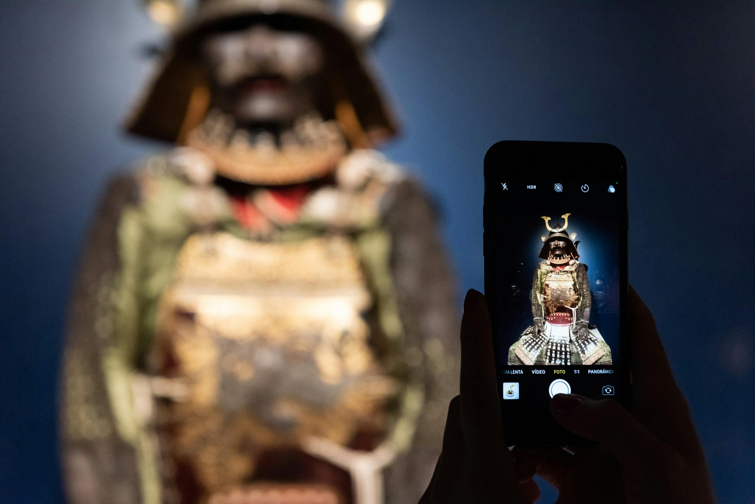 Osoba fotografuje detailní displej samurajského brnění pomocí smartphonu.