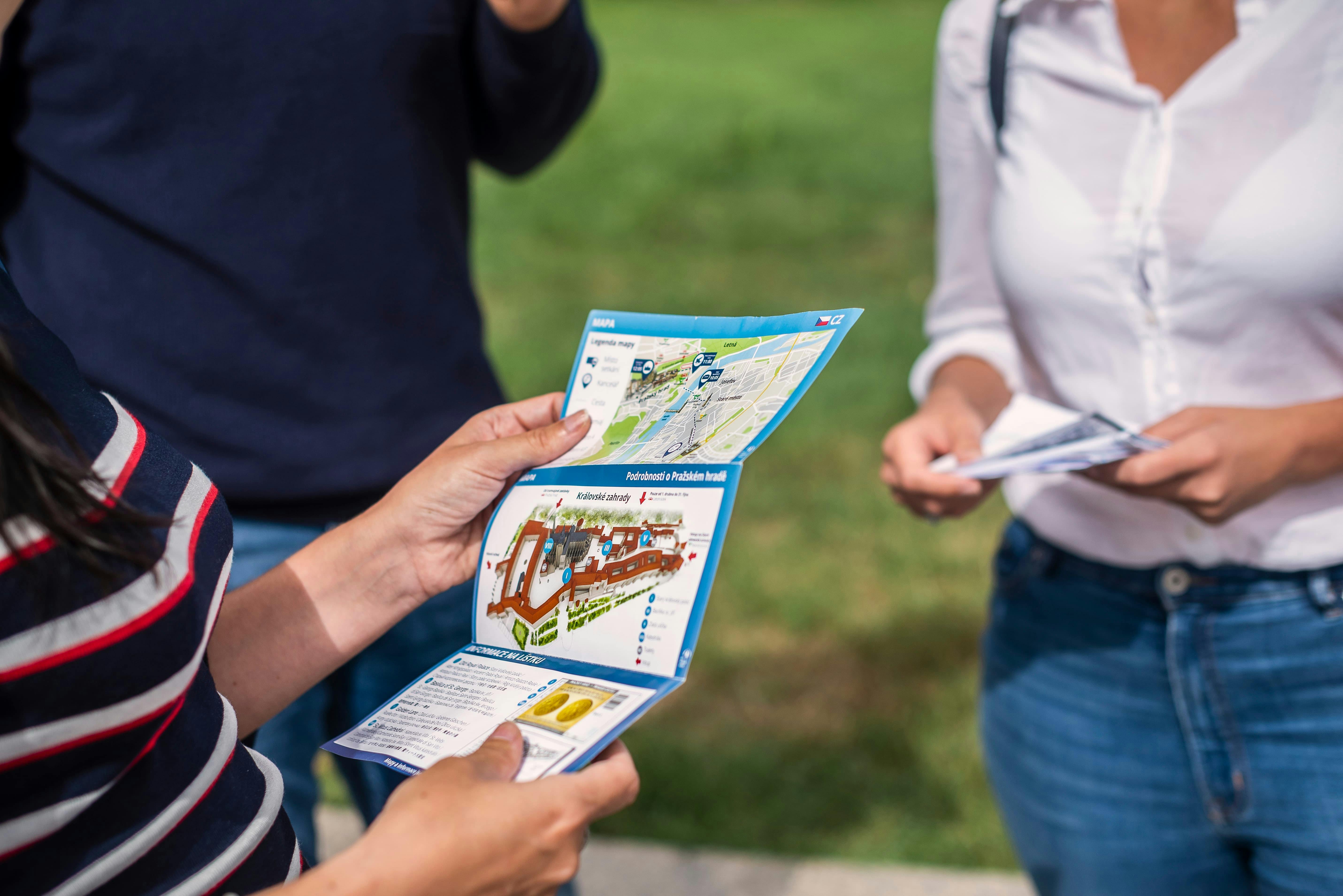 カラフルなパンフレットと地図を見ている数人。草を背景にしたアウトドアシーン。