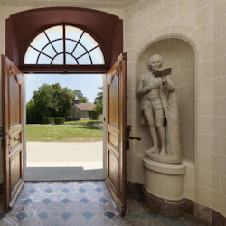 En öppen dörröppning med statyer på vardera sidan leder till en trädgård med en liten byggnad på avstånd.