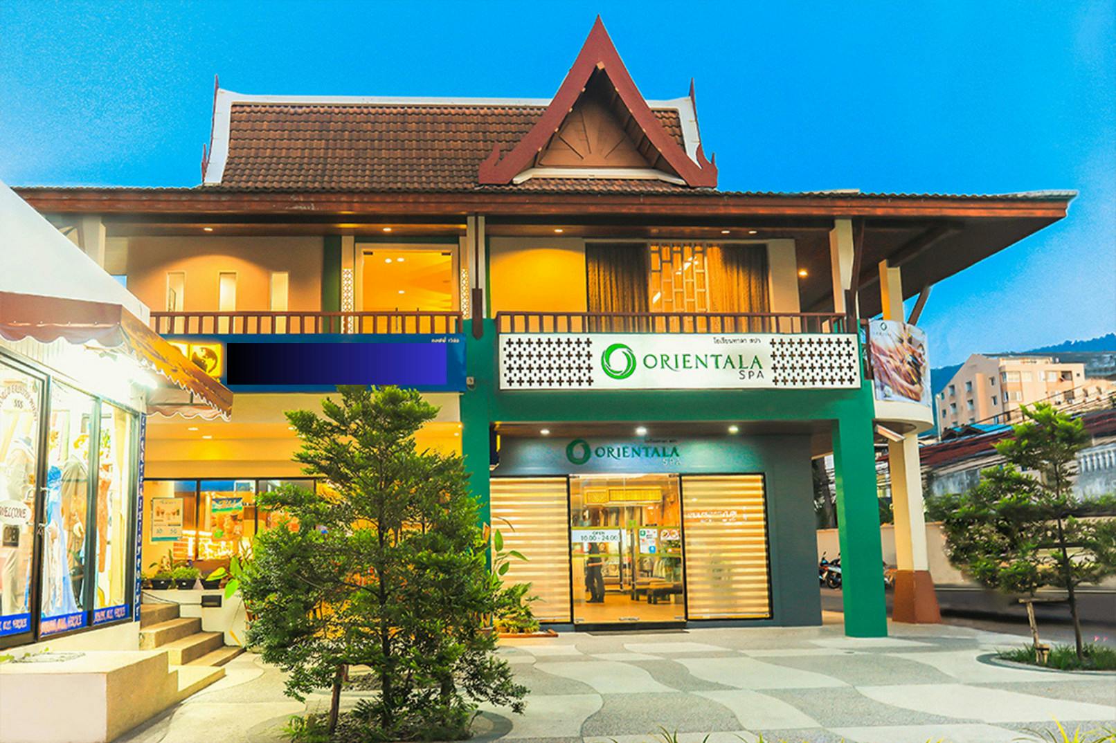 A two-story building with traditional architecture housing Orientala Spa, featuring a sign and a well-lit entrance.