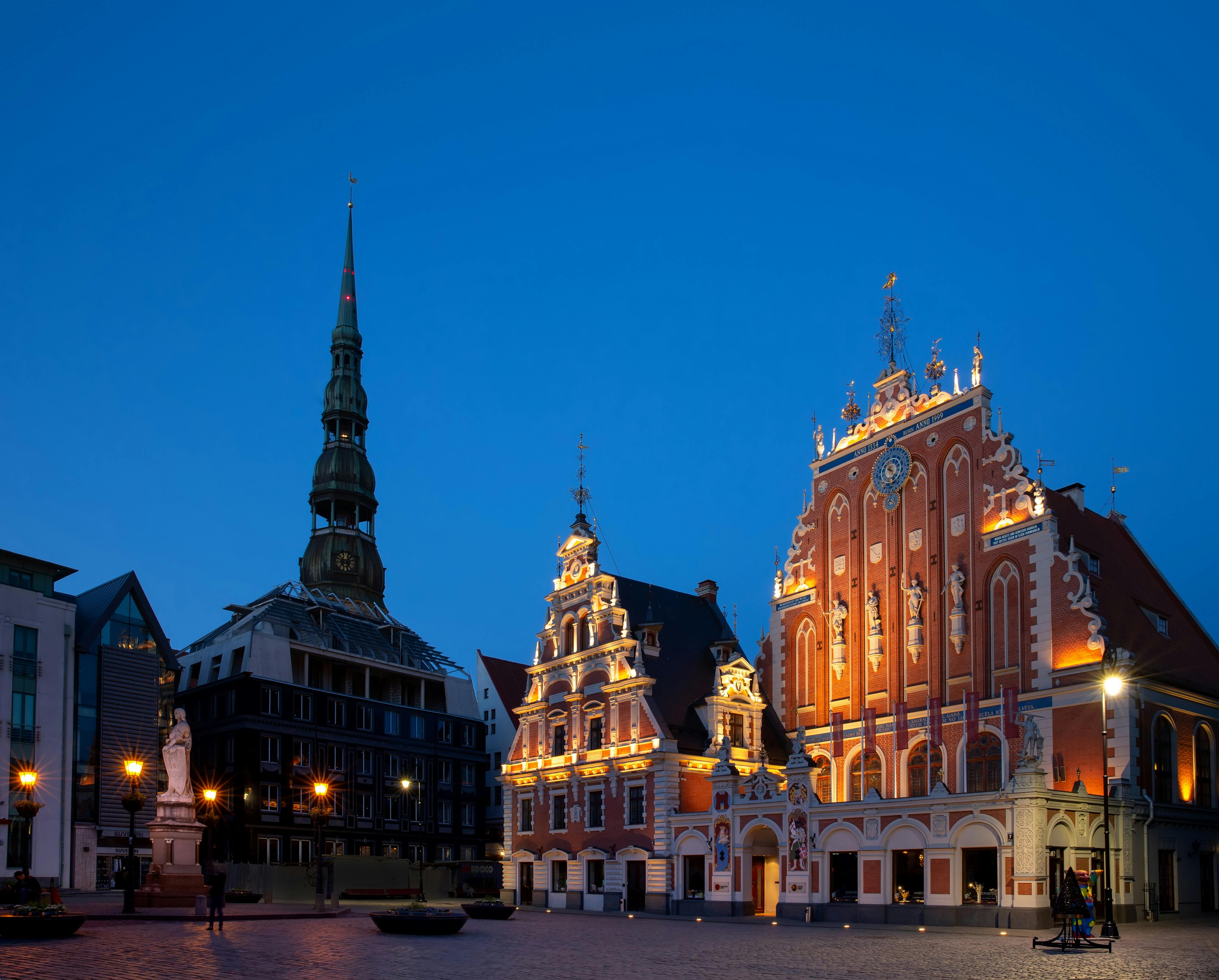 黄昏时的一个历史悠久的广场，拥有明亮的哥特式建筑和高大纤细的尖顶，俯瞰深蓝色的天空。
