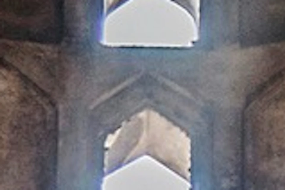 Historic stone building interior with sunlight streaming through intricate windows, arched doorways, and a central octagonal basin.