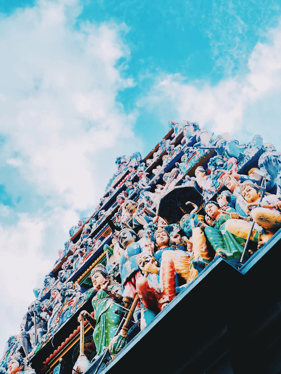 A colorful, intricately detailed section of a temple facade filled with numerous cherubic figures under a bright blue sky.
