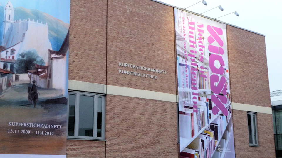 Building with a brick facade displaying the words "Kupferstichkabinett Kunstbibliothek" and a large vertical banner.