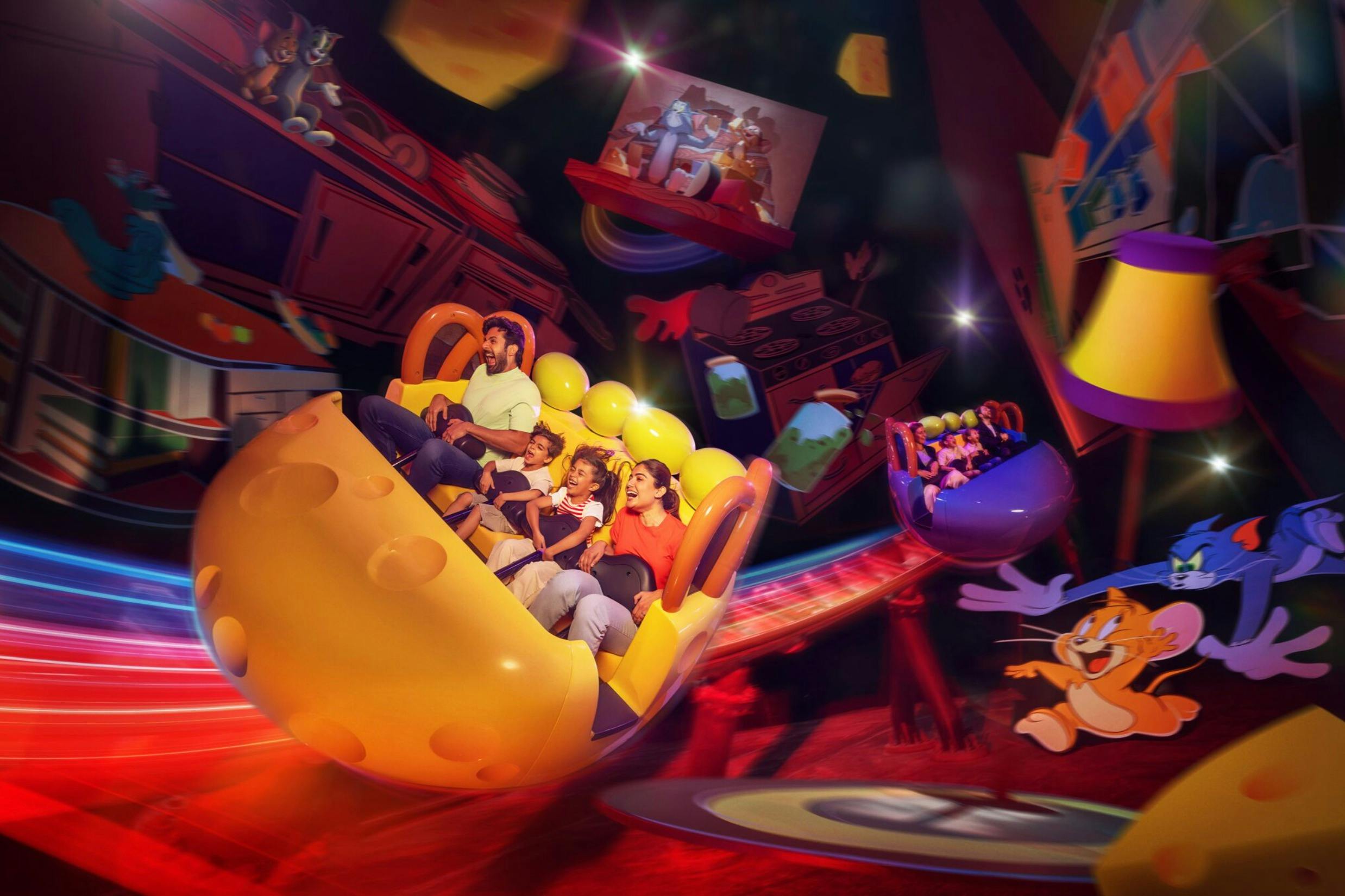 A family riding a vibrant yellow amusement park ride shaped like cheese, surrounded by cartoon-themed decor and lights.