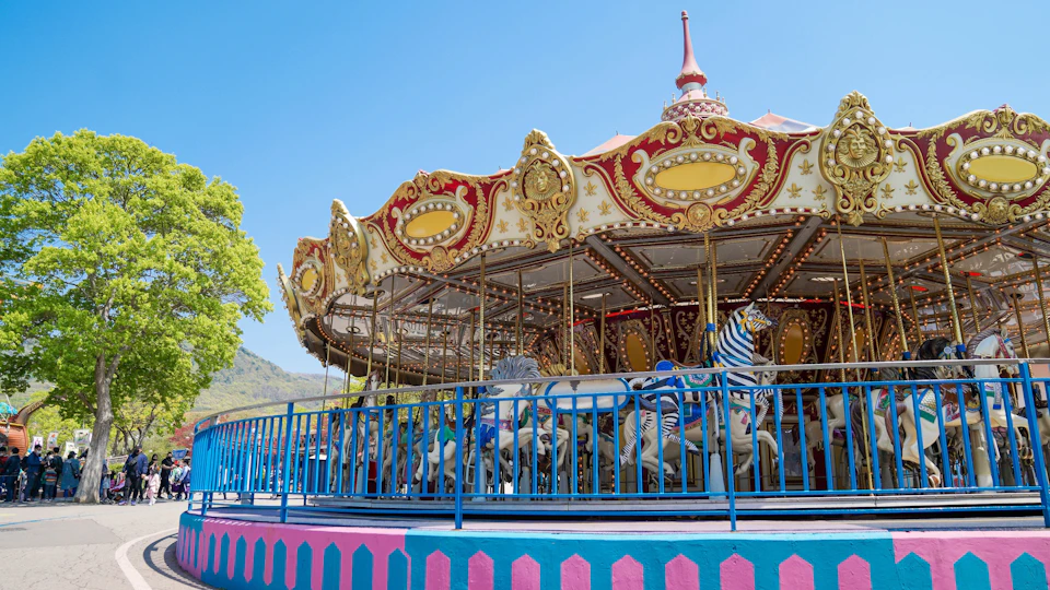 A colorful carousel with ornate decorations and animal-shaped seats, surrounded by a blue fence under a clear sky.