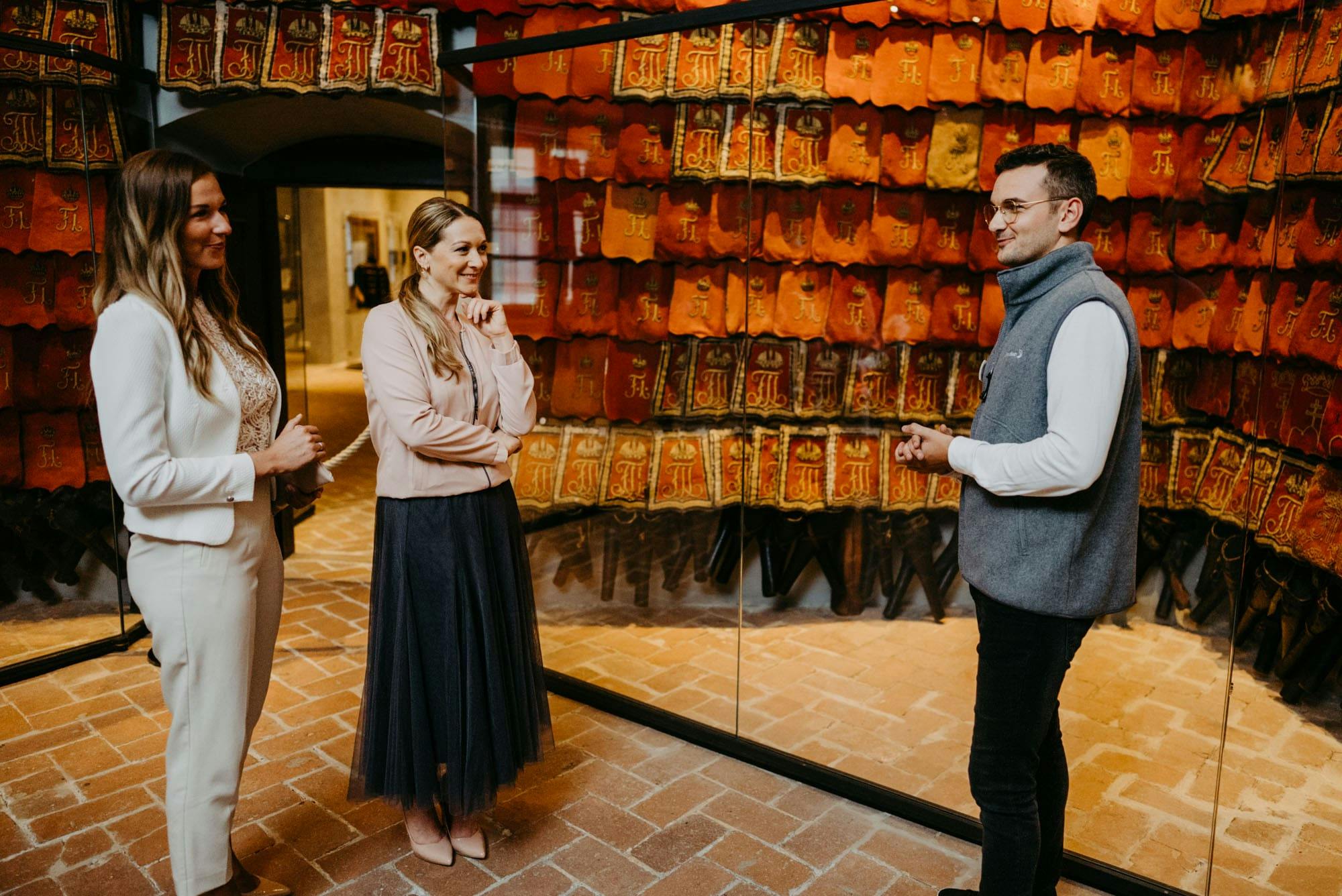 유리 뒤에 빨간색과 주황색 책 표지가 줄지어 있는 디스플레이 앞에 한 남녀가 서 있습니다.