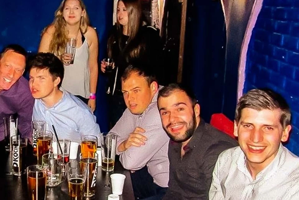 A group of smiling people drinking beer in a bar