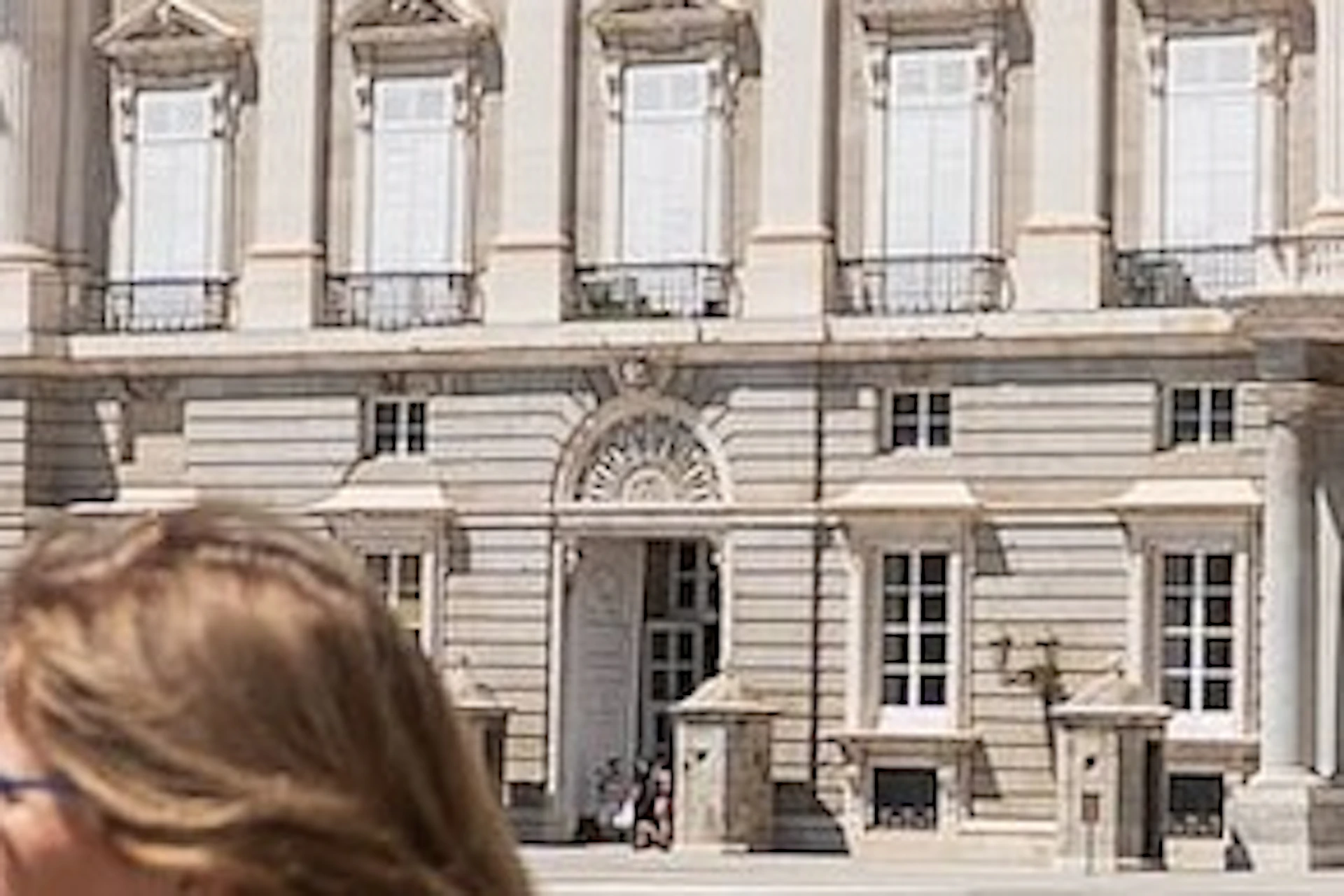 Group of people in front of an ornate, historic building with a clear blue sky.