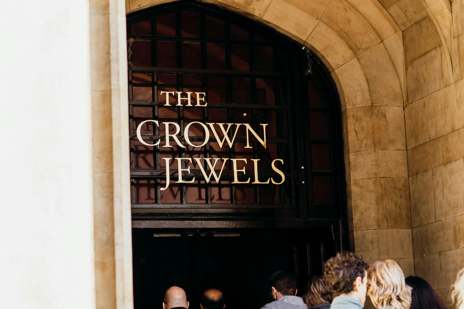 People entering an arched doorway with a sign that reads "The Crown Jewels."