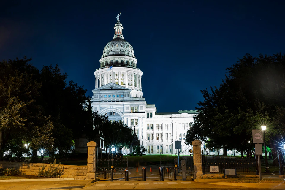 Large white, capitol building at night with lights shining on the front of the building.