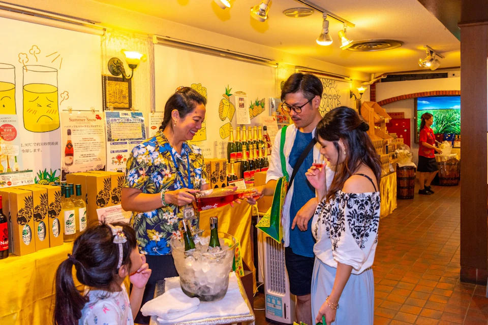 People at a store counter sampling food and beverages, with colorful bottles and decorations in the background.