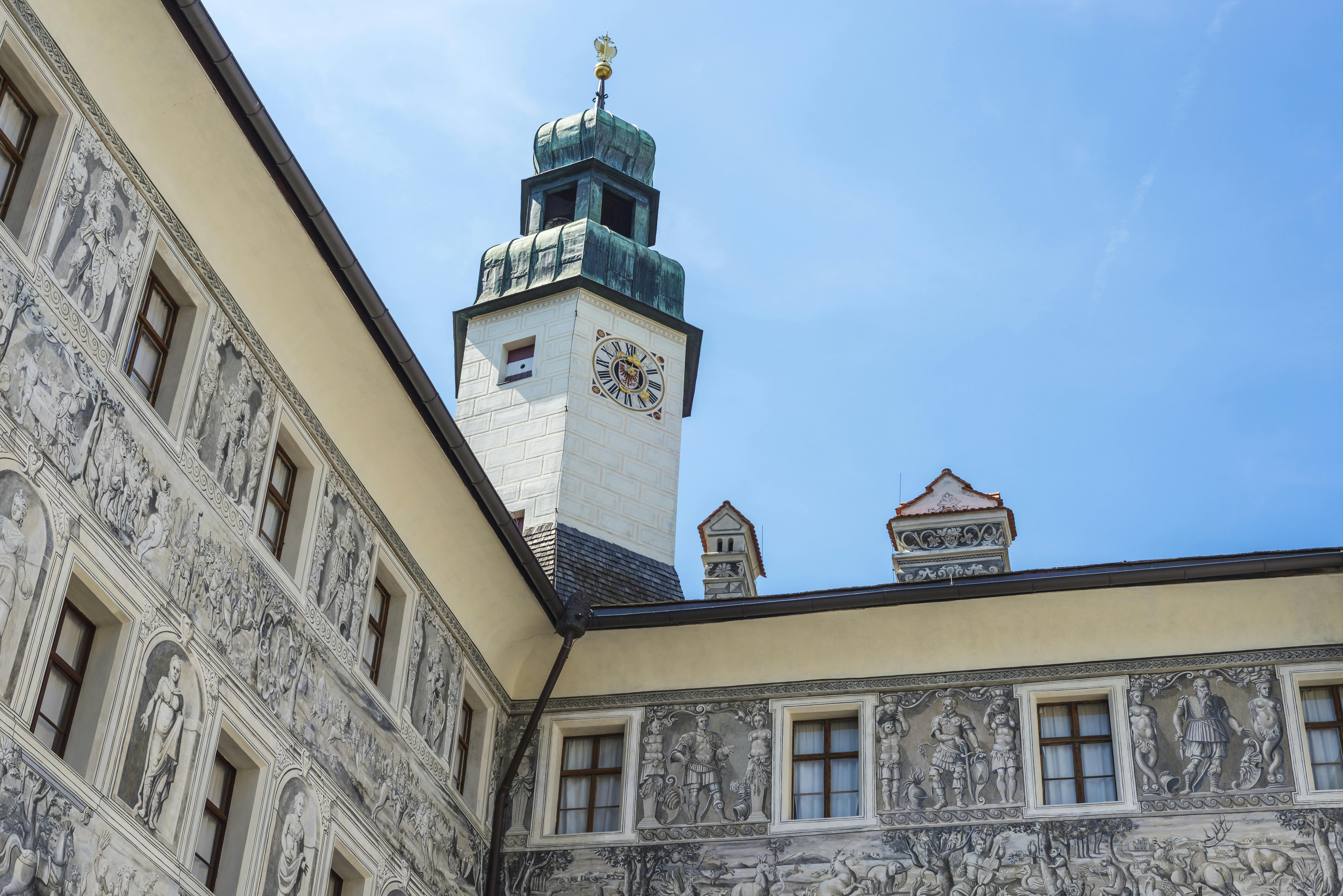 Historic building with detailed wall murals and a clock tower under a blue sky.