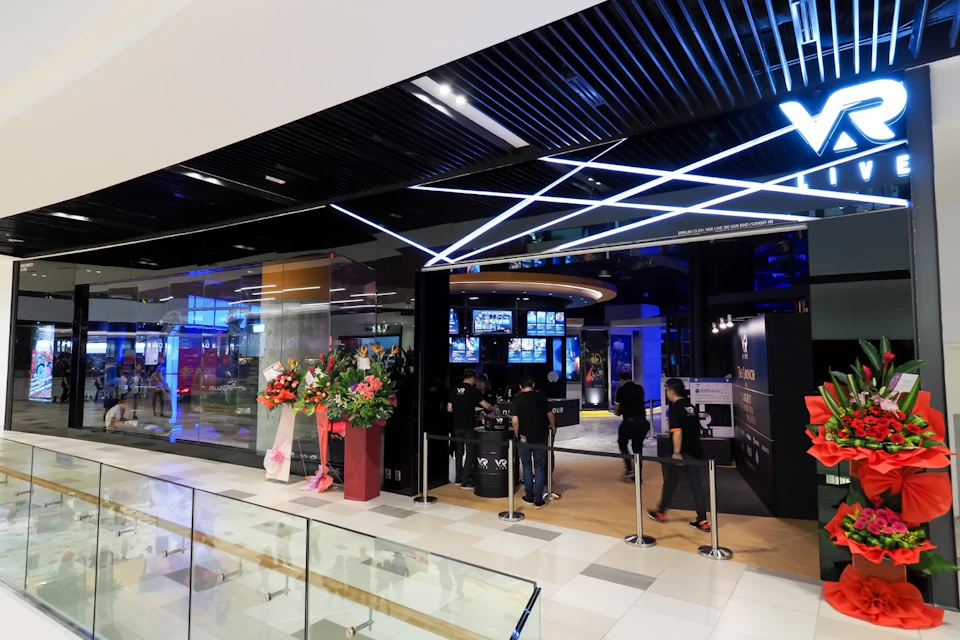 A modern storefront with a sleek design, featuring bright lighting, a digital display, and decorative floral arrangements.