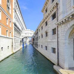 Smal kanal i Venedig med historiska byggnader på vardera sidan, förbundna med den slutna Suckarnas bro.