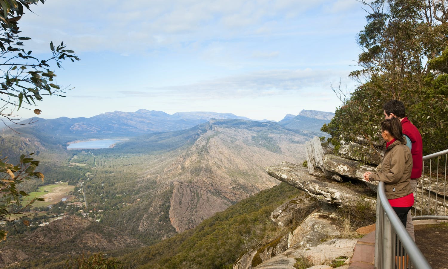 从岩石悬崖俯瞰绿色山谷，在一片多云的天空下远眺群山。