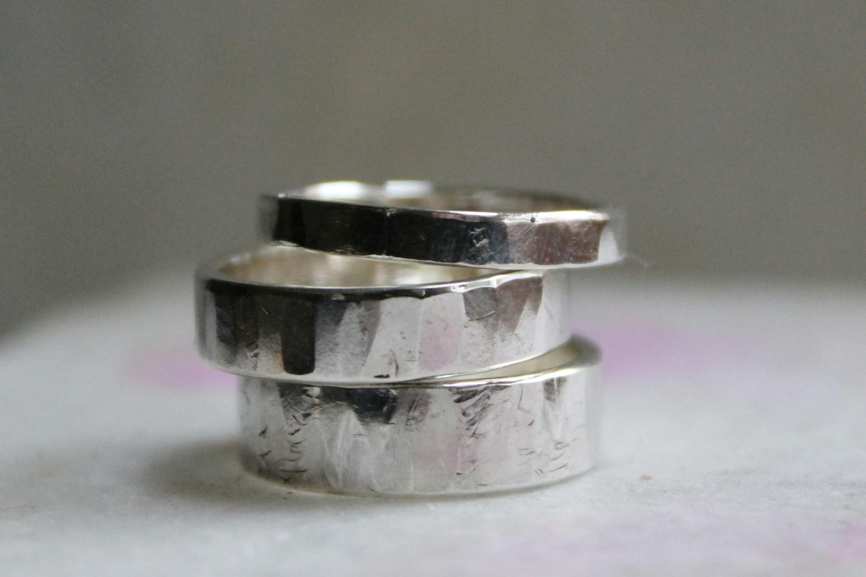 Three stacked silver rings with a hammered texture on a neutral background.