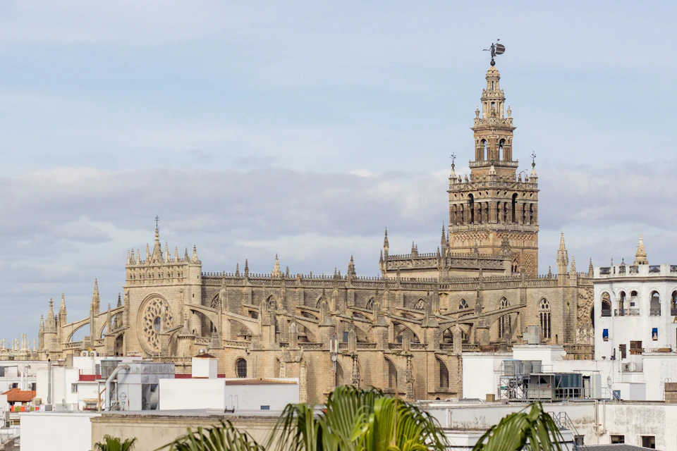 A historic Gothic-style cathedral with intricate details and a tall bell tower under a partly cloudy sky.