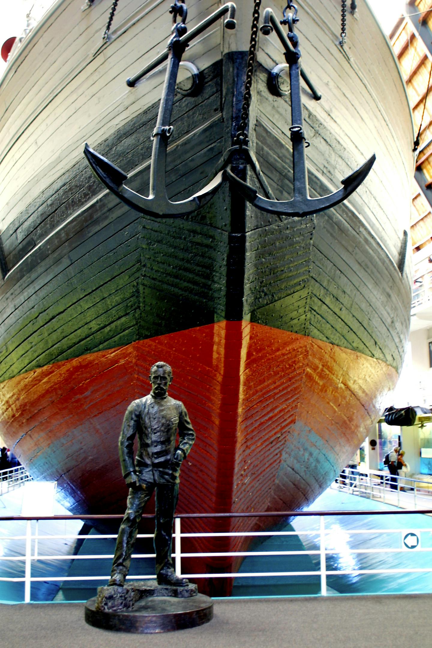 Μεγάλο τόξο πλοίου με διπλές άγκυρες, που εμφανίζεται σε εσωτερικούς χώρους πάνω από τα κιγκλιδώματα. Μπροστά στέκεται το άγαλμα ενός άνδρα με ναυτική ενδυμασία.