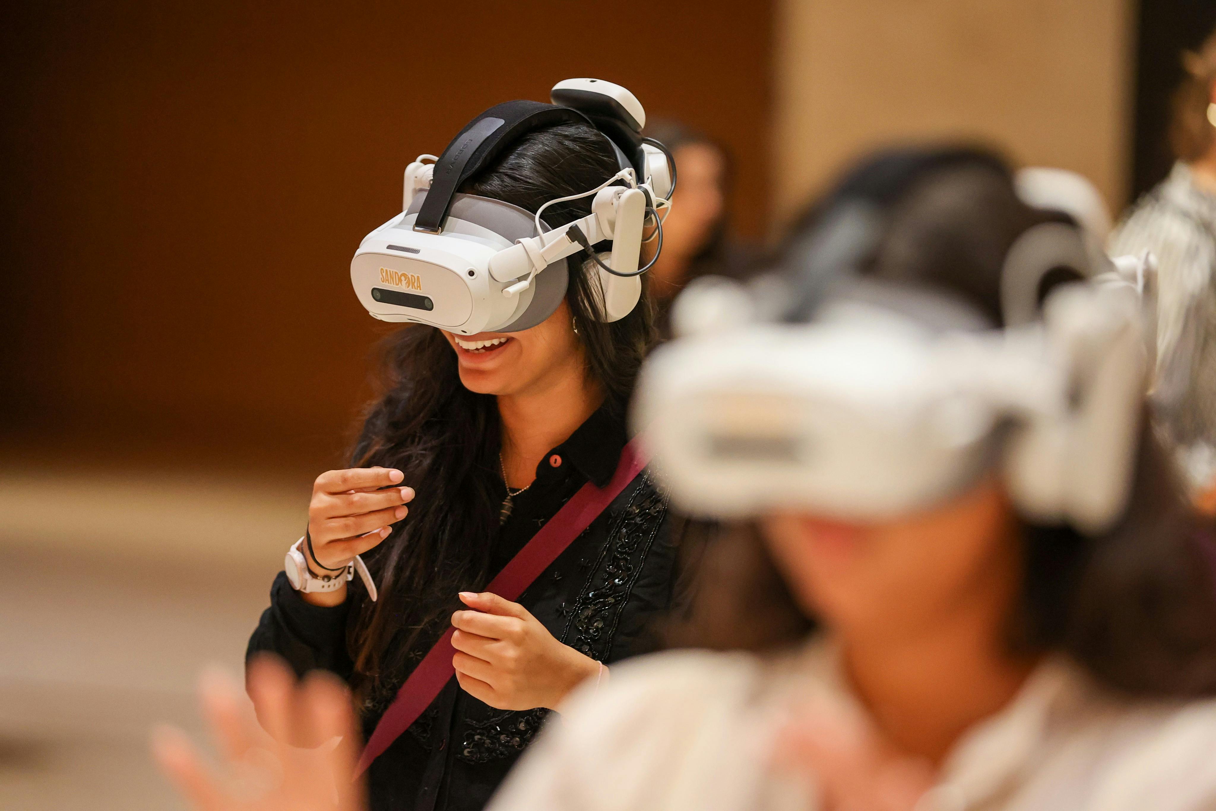Two people using virtual reality headsets, one smiling and engaged, in an indoor setting.