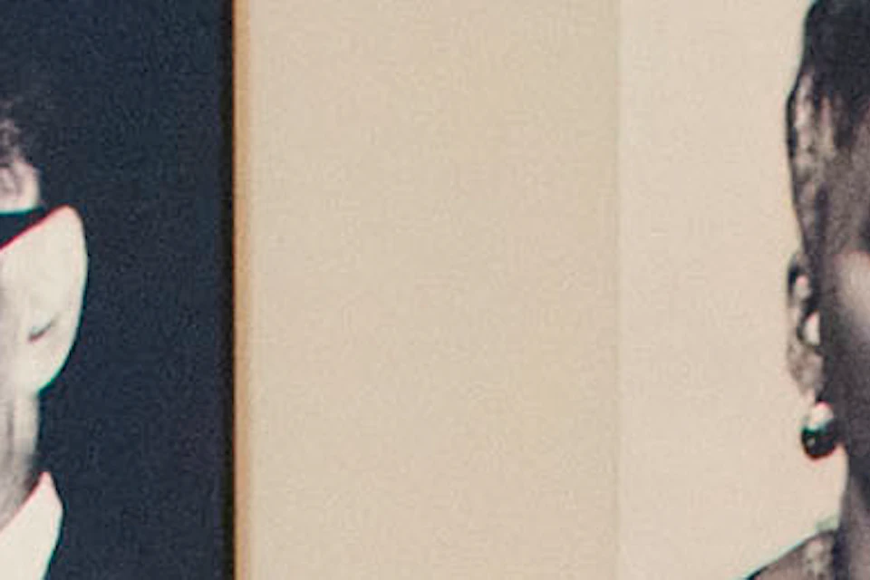 Two people observe and discuss portraits on a museum wall with informational text and a display screen.