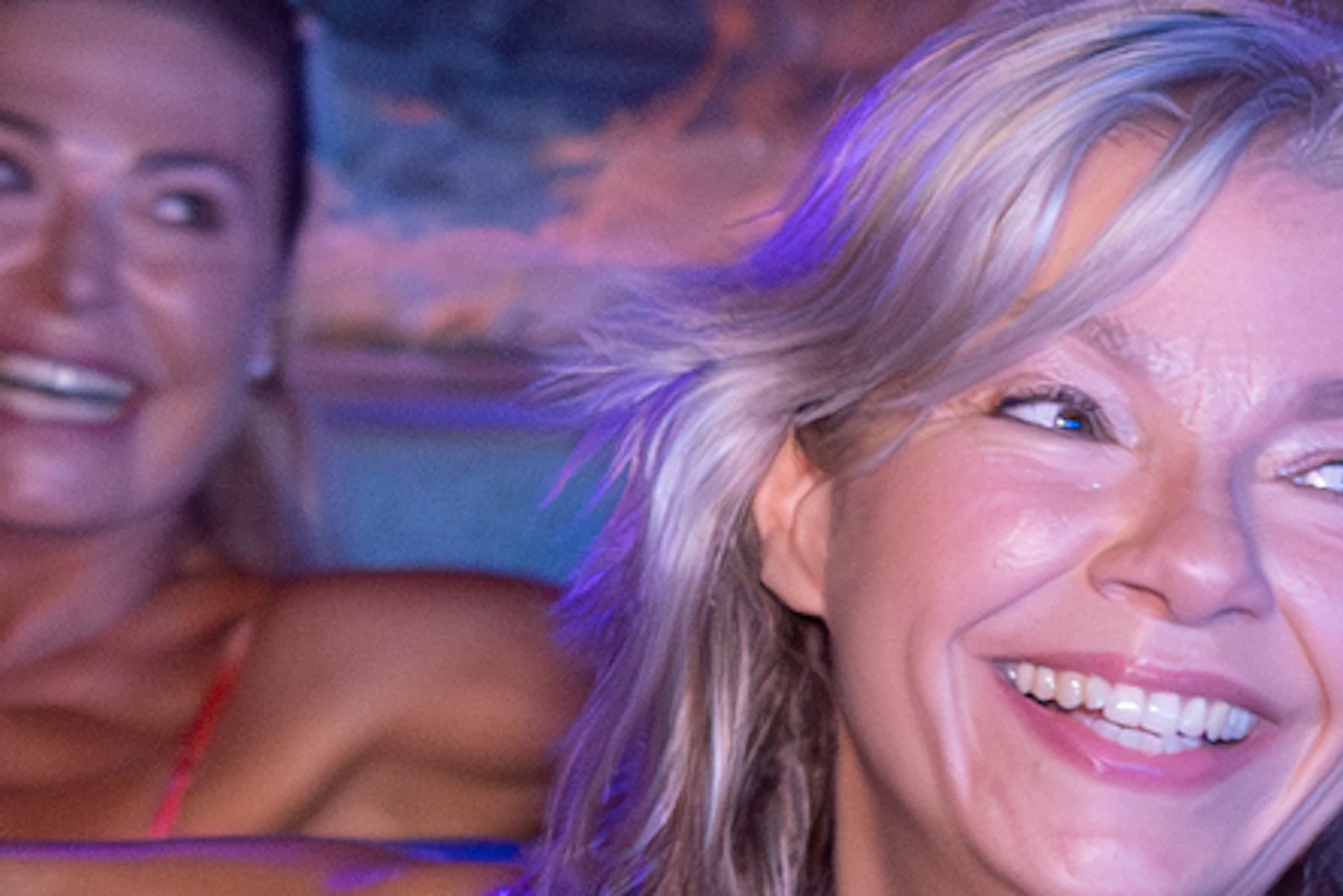People smiling while floating on blue inner tubes in an indoor aquatic cave with artificial marine decorations.