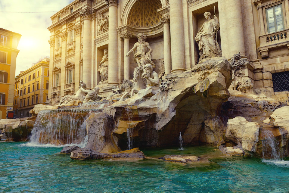 Ornate marble statues and cascading waterfalls at the Trevi Fountain, with clear turquoise water at its base.
