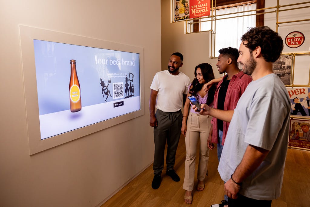 Four people interact with a digital display in a room decorated with vintage beer signs. One person holds a smartphone.