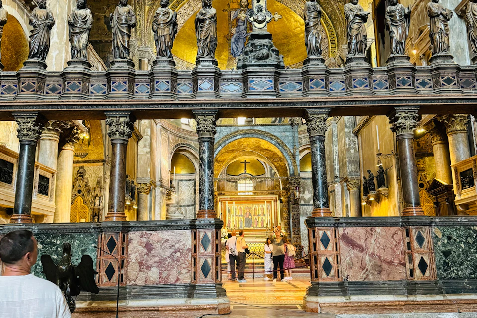 A group of people admire ornate religious artwork and statues in a richly decorated cathedral interior with golden domes.