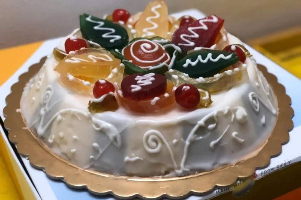 白色磨砂蛋糕，上面有五颜六色的果冻糖果，金边盘子上有装饰性糖衣。