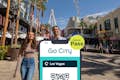 Las Vegas Explorer Pass da Go City exibido em um smartphone com um casal de turistas na Las Vegas Strip ao fundo