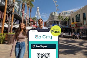 Las Vegas Explorer Pass van Go City op een smartphone met een toeristisch stel op de Las Vegas Strip op de achtergrond