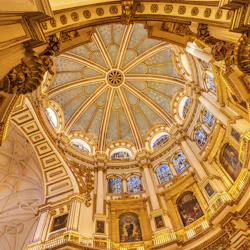 Utsmyckad interiör i en kupol med invecklade gulddetaljer, målningar, glasmålningar och dekorativa kolumner.