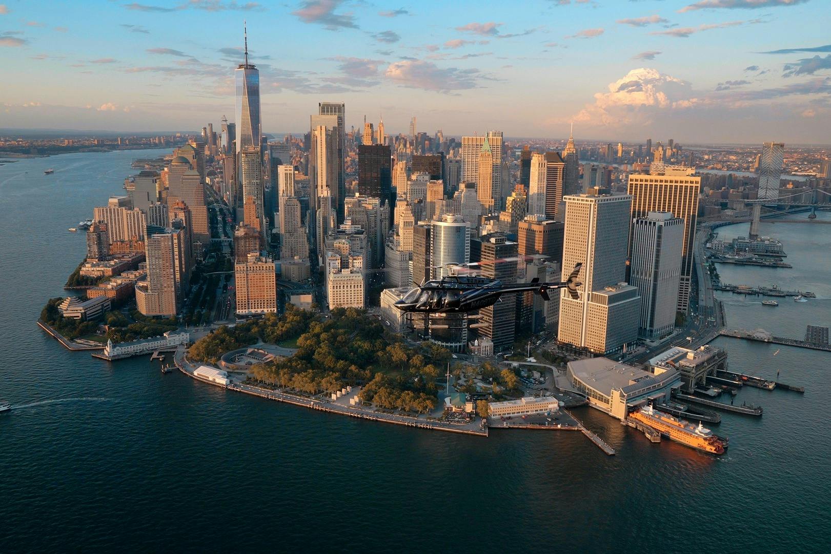 Vista aérea de um helicóptero a sobrevoar a zona ribeirinha perto dos arranha-céus na baixa de Manhattan ao pôr do sol.