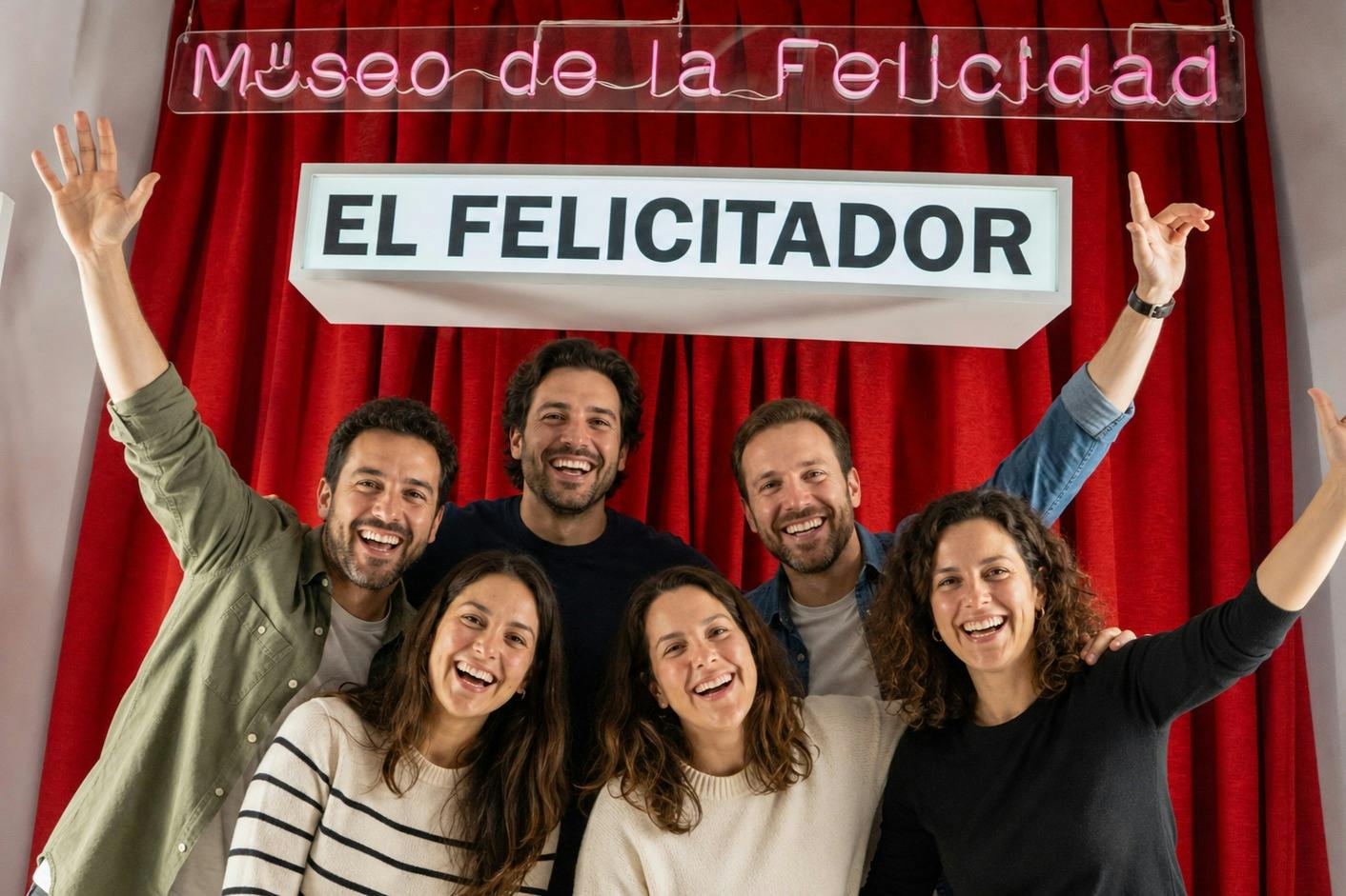 Seis pessoas sorridentes estão em frente a uma cortina vermelha, debaixo de um letreiro onde se lê «El Felicitador» em letras pretas.