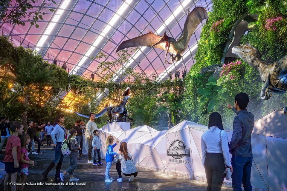 People exploring a Jurassic World-themed exhibit with dinosaur statues and a large pterosaur model in a glass-domed space.
