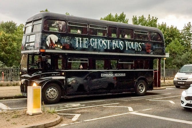 Ένα μαύρο διώροφο λεωφορείο με την ένδειξη "The Ghost Bus Tours" και "Edinburgh Necrobus" σταθμευμένο σε έναν δρόμο με δέντρα στο παρασκήνιο.