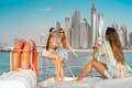 meisjes genieten van zeiltocht en poseren met skyline van Dubai