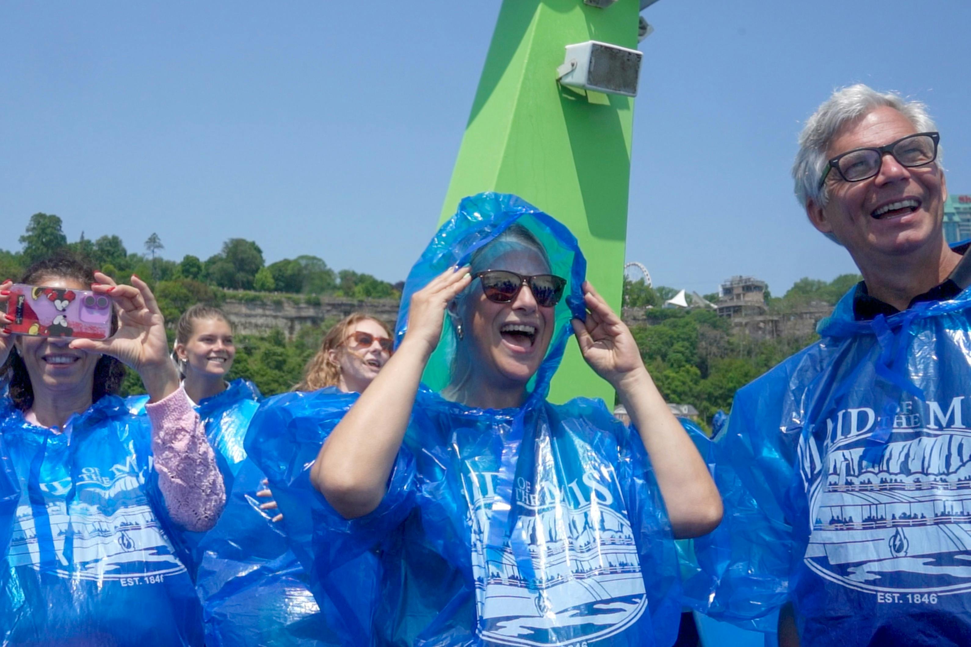 푸른 판초와 선글라스를 끼고 푸르름과 푸르름을 배경으로 웃고 있는 사람들.