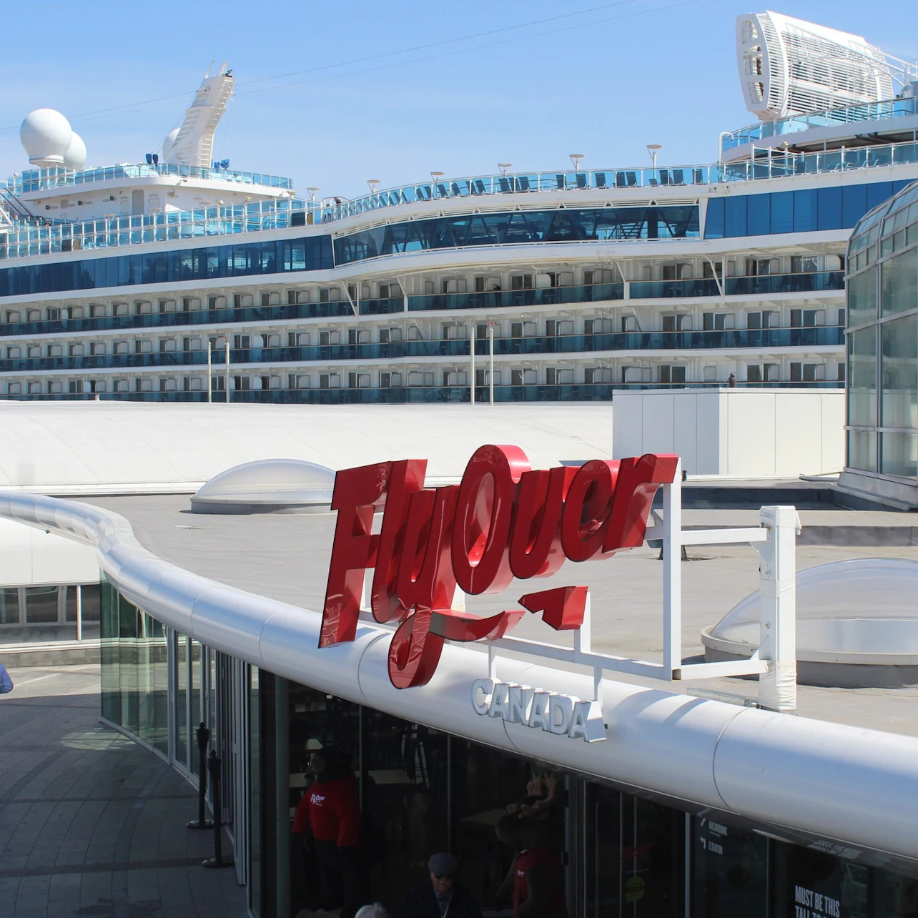 Red "FlyOver" sign on a building with a cruise ship in the background.