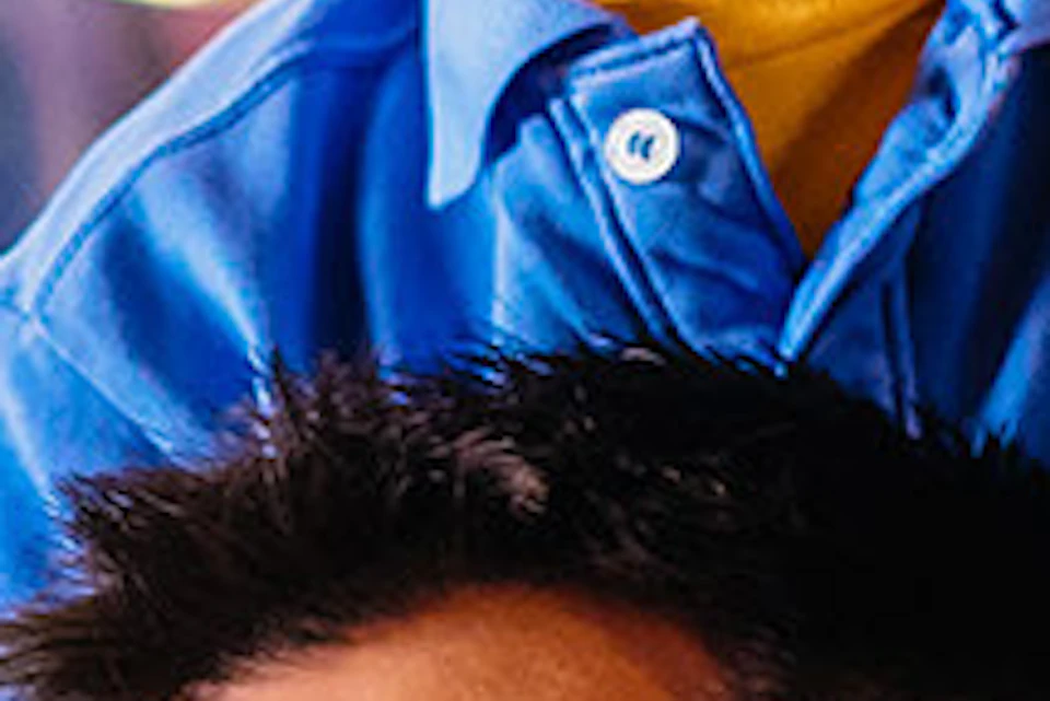 Smiling man carrying a boy on his shoulders inside a colorful indoor play area with climbing structures.