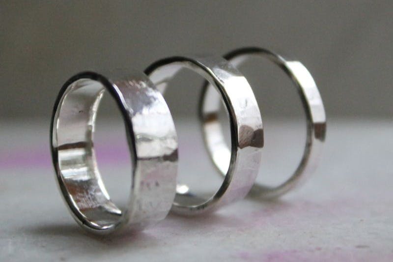 Tři zatlučené stříbrné prsteny stojící svisle na světle zbarveném povrchu.