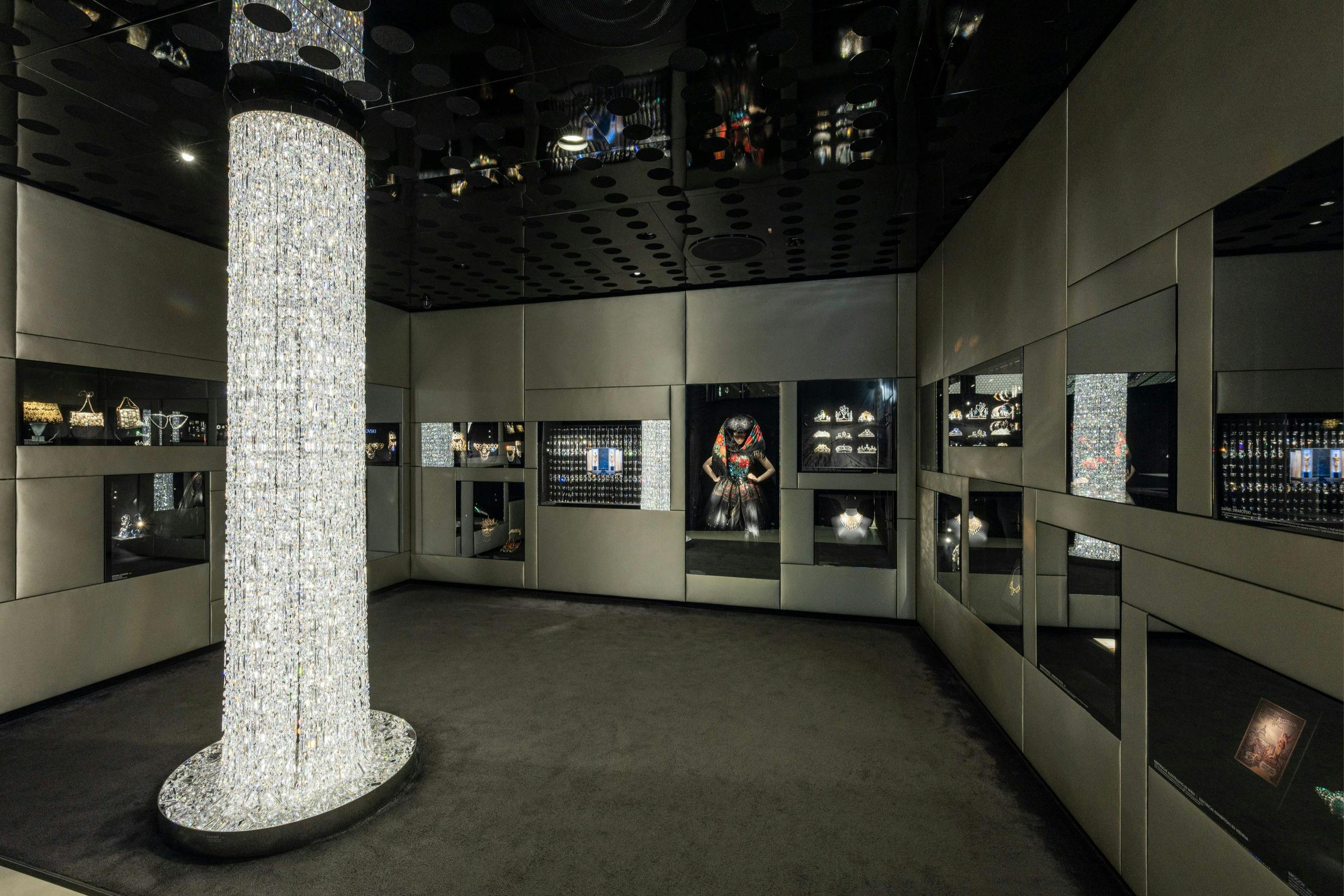 大きなシャンデリア、反射壁、宝石や装飾品を展示するさまざまなディスプレイを備えた薄暗い部屋。