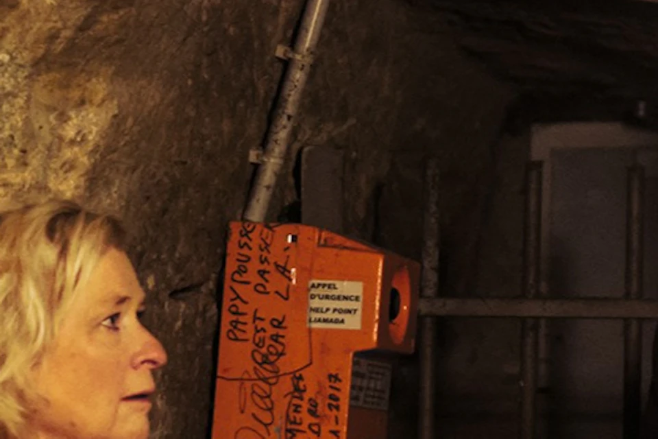 A group of people in a dimly lit underground setting, with a guide explaining something to the group.