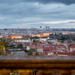 Med utsikt över en stadsbild i skymningen, med en flod med upplysta broar och historiska byggnader med röda tak.