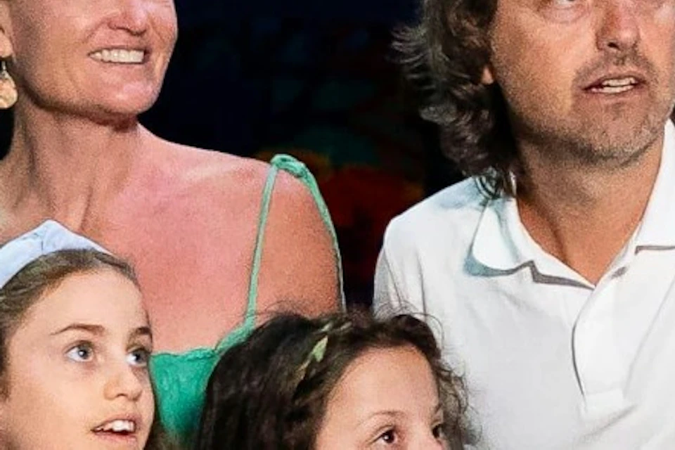 A family of four standing on a walkway through an underwater tunnel, surrounded by marine life and illuminated by aquarium lighting.
