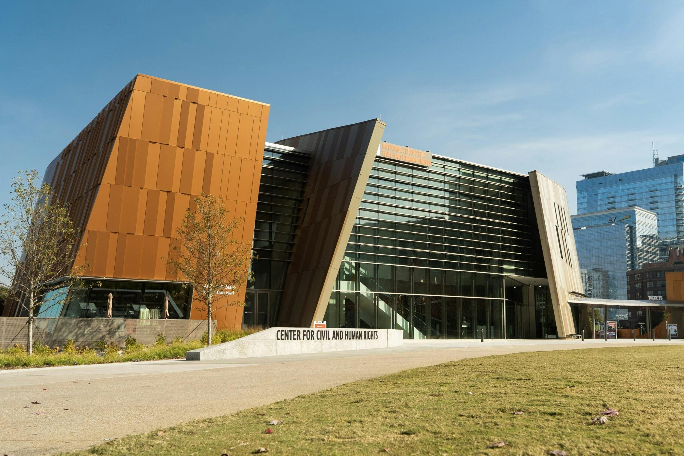晴れた空の下、市民と人権のためのセンターとして特定された、角のあるデザインとガラスのファサードを備えたモダンな建物。