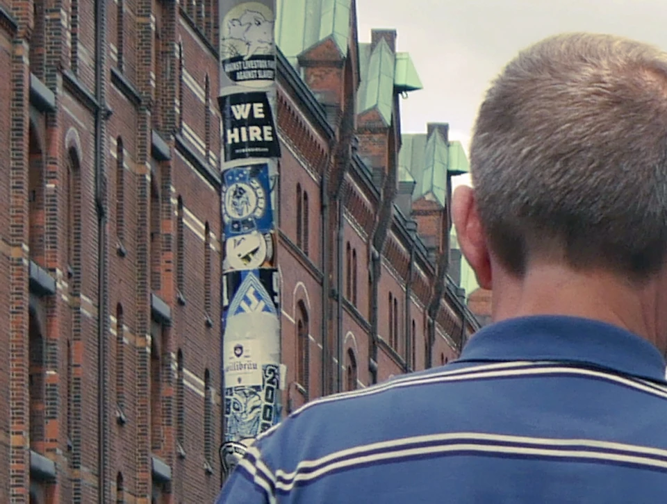 A tour group stands on a bridge surrounded by brick buildings, with one person speaking and others listening attentively.