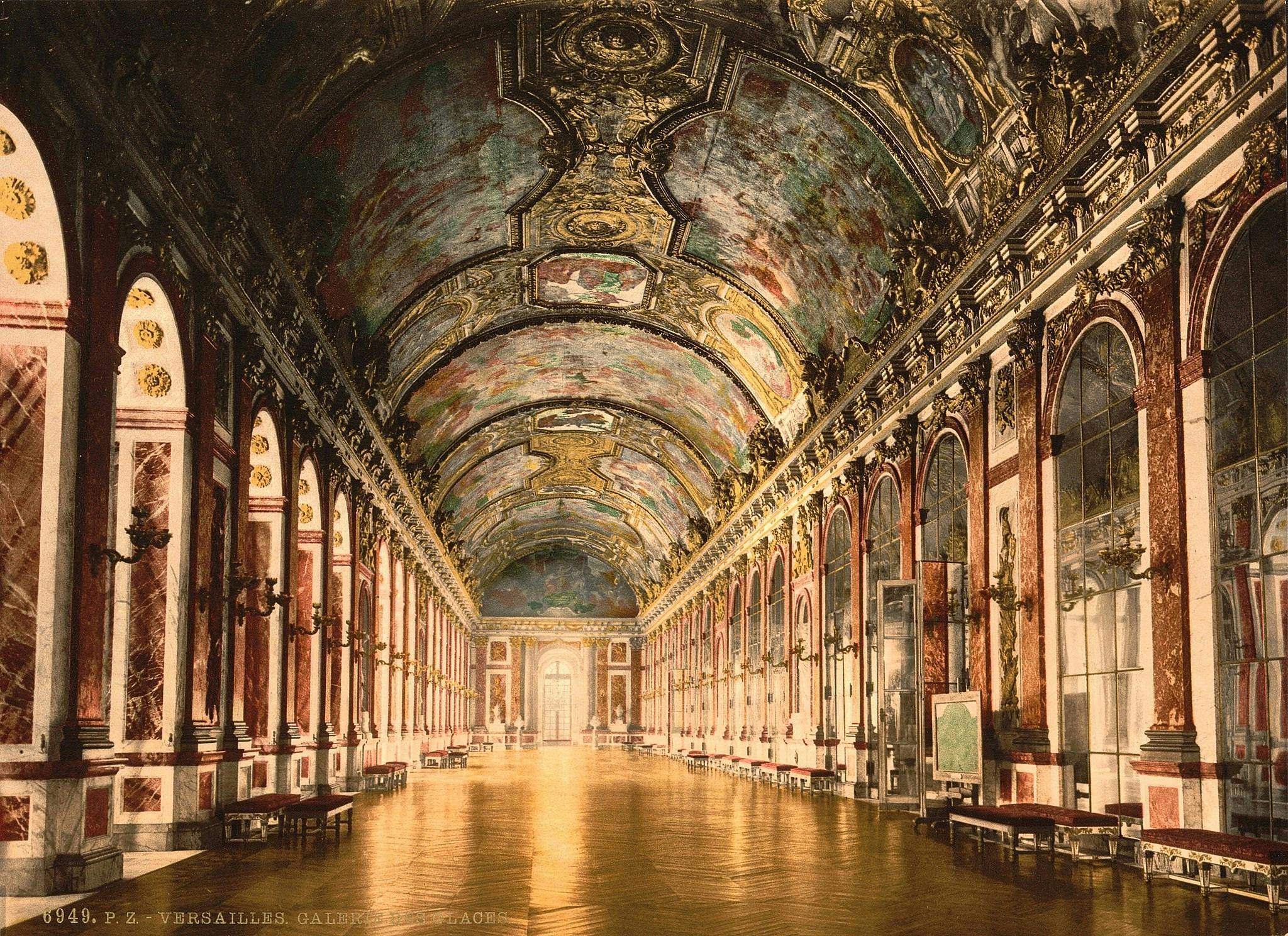 An opulent hall with a decorative arched ceiling, marble walls, and floor-to-ceiling mirrors reflecting sunlight. Benches line the walls.